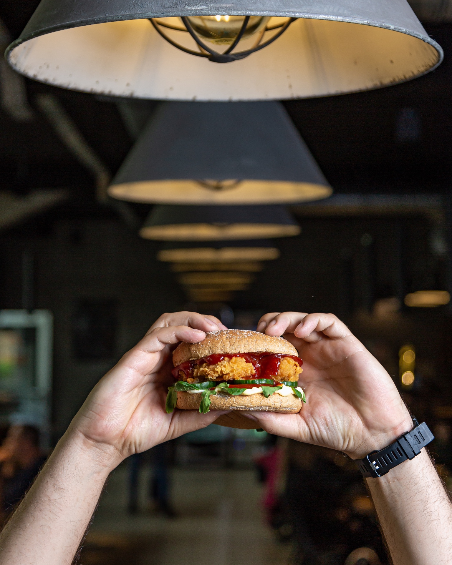 Burger w dłoniach we wnętrzu lokalu